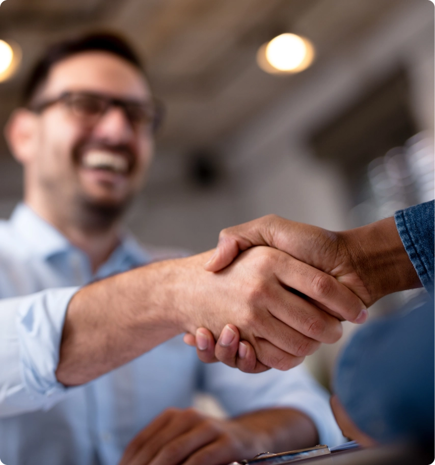 Two people shaking hands at desk