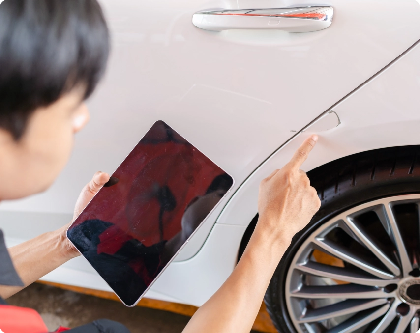 Man with tablet checking damage on vehicle